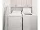 Bright laundry room with washer, dryer, ironing board, and overhead cabinets at 5596 Nw 57Th St, Ocala, FL 34482