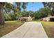 Ranch home with a long driveway, flags, and outbuilding at 581 Ne 44Th Ave, Ocala, FL 34470