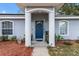 Inviting front entrance with an arched entryway, a blue front door, and lush landscaping at 603 Marion Oaks Blvd, Ocala, FL 34473