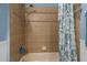 Tiled shower and bathtub with neutral tile, a shower caddy and decorative shower curtain at 603 Marion Oaks Blvd, Ocala, FL 34473