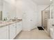Bright bathroom with double granite vanity, white cabinets, a tiled floor, and a glass shower at 6175 Sw 88Th Loop, Ocala, FL 34476