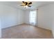 Bright bedroom with a ceiling fan, neutral carpet, and a large window providing natural light at 6250 Se 88Th St, Ocala, FL 34472