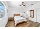 Bedroom features ceiling fan, wood look flooring, window with backyard view, and ensuite bathroom at 8905 Sw 76Th Ln, Ocala, FL 34481
