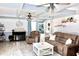 Cozy living room with a fireplace, ceiling fans, hardwood floors, and comfortable seating area at 25600 Se 152Nd Pl, Umatilla, FL 32784