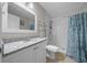 This bathroom features a white vanity with granite countertops and a white tiled shower with seashell-themed curtain at 5018 Se 106Th Pl, Belleview, FL 34420