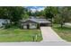 Charming single-story home featuring a spacious driveway and lush green lawn and mature trees at 5018 Se 106Th Pl, Belleview, FL 34420