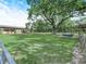 Lush green backyard featuring a large tree, metal fencing, and an animal shelter at 4880 Bannon Island Rd, Haines City, FL 33844