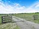 Rustic metal and wood gate marking the entrance to a gravel driveway with a rural backdrop at 4880 Bannon Island Rd, Haines City, FL 33844