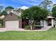 Charming single-story home with manicured lawn, brick driveway, mature tree, and two-car garage at 416 Sandestin Dr, Winter Haven, FL 33884