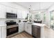 Modern kitchen featuring stainless steel appliances, white cabinets, quartz countertops, and hardwood floors at 6047 Cason Way, Lakeland, FL 33812