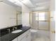 Bathroom with black granite vanity, white cabinets, and tub with gold-trimmed glass doors at 5660 Sandpipers Dr, Lakeland, FL 33809