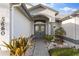 Elegant home entrance with a decorative glass front door, brick pathway, and meticulously maintained landscaping at 5660 Sandpipers Dr, Lakeland, FL 33809