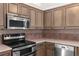 Close up of a stainless steel range and microwave with light-colored cabinets and tiled backsplash at 5660 Sandpipers Dr, Lakeland, FL 33809