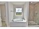 Bathroom features a soaking tub under a window, and a tiled glass shower at 4039 Tullamore Ln, Auburndale, FL 33823