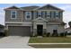 Two-story house with gray siding, stone accents, and landscaping at 605 Sarner Pass Way, Winter Haven, FL 33881