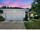 Inviting single-story home with a two car garage, decorative fountain, and warm exterior lighting at 2158 Mirasol Dr, Winter Haven, FL 33881