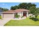 Tan house with red door, landscaping, and two-car garage at 5643 Fischer Dr, Lakeland, FL 33812