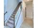 A staircase with carpeted steps and a white railing, lit by natural light at 1476 Leamington Lane, Winter Haven, FL 33884