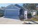 Two-story home with light blue exterior, stone accents, and a two-car garage at 296 Krenson Bay Loop, Winter Haven, FL 33881