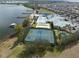 An aerial view of tennis courts, pool, and clubhouse with the lake and residential neighborhood in the background at 4104 Martindale Loop, Winter Haven, FL 33884