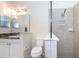 Well-lit bathroom featuring a sink, a toilet, and a tiled walk-in shower with a built-in shelving unit at 4104 Martindale Loop, Winter Haven, FL 33884