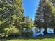 Scenic view of a tranquil pond surrounded by mature trees, reflecting the clear blue sky at 4104 Martindale Loop, Winter Haven, FL 33884