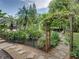 Charming backyard featuring a pergola covered in flowering vines, surrounded by lush greenery, and a stone walkway at 3808 Gaines Dr, Winter Haven, FL 33884