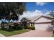 Pink house with stone accents, mature trees, and a well-manicured lawn at 3832 Traditions N Blvd, Winter Haven, FL 33884