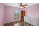 Bedroom featuring hardwood floors, a window overlooking outside, ceiling fan, and white dresser at 720 S Morrison Ave, Fort Meade, FL 33841