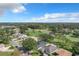 An aerial view of a neighborhood and golf course in a lush, green landscape under a blue sky with scattered clouds at 579 Saint Andrews Rd, Winter Haven, FL 33884