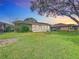 The green lawn is surrounded by shrubbery. The back of the house shows a porch filled with windows at 579 Saint Andrews Rd, Winter Haven, FL 33884