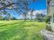 Expansive backyard view featuring a lush green lawn, mature trees, and golf carts in the distance at 579 Saint Andrews Rd, Winter Haven, FL 33884