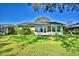 Back of house with an enclosed porch with lots of windows, green lawn, and landscaping at 579 Saint Andrews Rd, Winter Haven, FL 33884