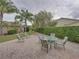 Brick patio with an outdoor dining set and a green hedge, surrounded by palm trees at 4189 Limerick Dr, Lake Wales, FL 33859