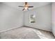 Bright bedroom with neutral carpet, ceiling fan, and view of a fenced yard at 2821 Sheldon St, Lakeland, FL 33813