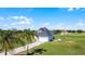 Aerial view of the light-blue home, lush green lawn, palm trees, and gravel driveway on a sunny day at 4071 Albritton Rd, St Cloud, FL 34772