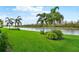 Lush green lawn, palm trees, and a serene canal view at 473 Adams View Ln, Auburndale, FL 33823