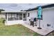 Covered patio has a barbecue and blue umbrella with a white wall in this backyard at 105 Elliott Ln, Winter Haven, FL 33884