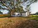 Backyard of home, showcasing new paint, windows, and large trees at 2002 Sutton Rd, Lakeland, FL 33810