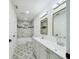 Modern bathroom featuring a double vanity, tub with marble-style tiling, and patterned tile floors at 2002 Sutton Rd, Lakeland, FL 33810