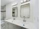 Bright bathroom featuring a double vanity with two mirrors, modern lighting, and marble-style tile in the shower at 2002 Sutton Rd, Lakeland, FL 33810