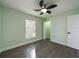 Inviting bedroom with wood-look flooring, white trim, light green paint, and a modern ceiling fan at 2002 Sutton Rd, Lakeland, FL 33810