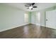 Bright bedroom with light green walls, wood-look flooring, a ceiling fan, and a view into the ensuite bathroom at 2002 Sutton Rd, Lakeland, FL 33810