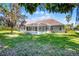 Home's backyard featuring a screened-in pool, green grass, and mature trees at 324 Hamilton Shores Ne Dr, Winter Haven, FL 33881