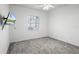 Neutral bedroom features plush carpet, a ceiling fan, a mounted television, and a large window at 324 Hamilton Shores Ne Dr, Winter Haven, FL 33881