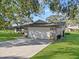 Side view showcasing a well-maintained two-car garage, garden urns, and lush green lawn at 4570 Chambliss Rd, Winter Haven, FL 33884