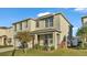 Two-story house with light beige siding, a tree, and landscaping at 935 Waterville Dr, Auburndale, FL 33823