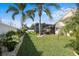 Well-manicured backyard with tropical landscaping, green lawn, and a screened in patio at 5808 Driftwood Dr, Winter Haven, FL 33884