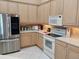 Well-maintained kitchen with stainless steel refrigerator, white appliances and natural wood cabinets at 4101 Limerick Dr, Lake Wales, FL 33859