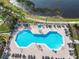 Aerial view of a large community pool with plenty of chairs for lounging, with a lake in the background at 4101 Limerick Dr, Lake Wales, FL 33859